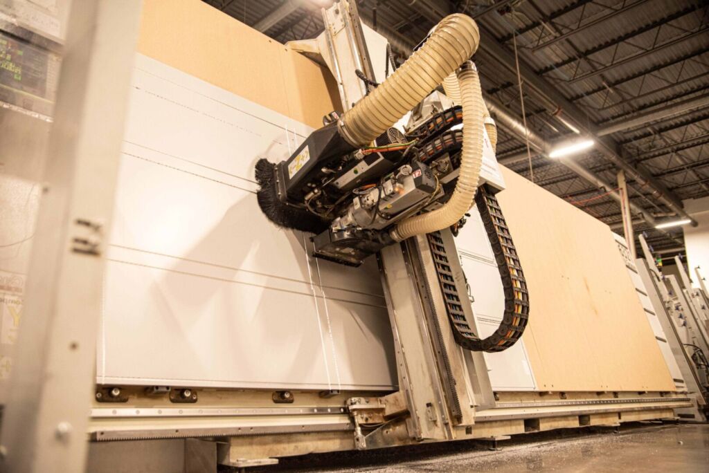 Close-up of CNC machine arm with vacuum hose attached