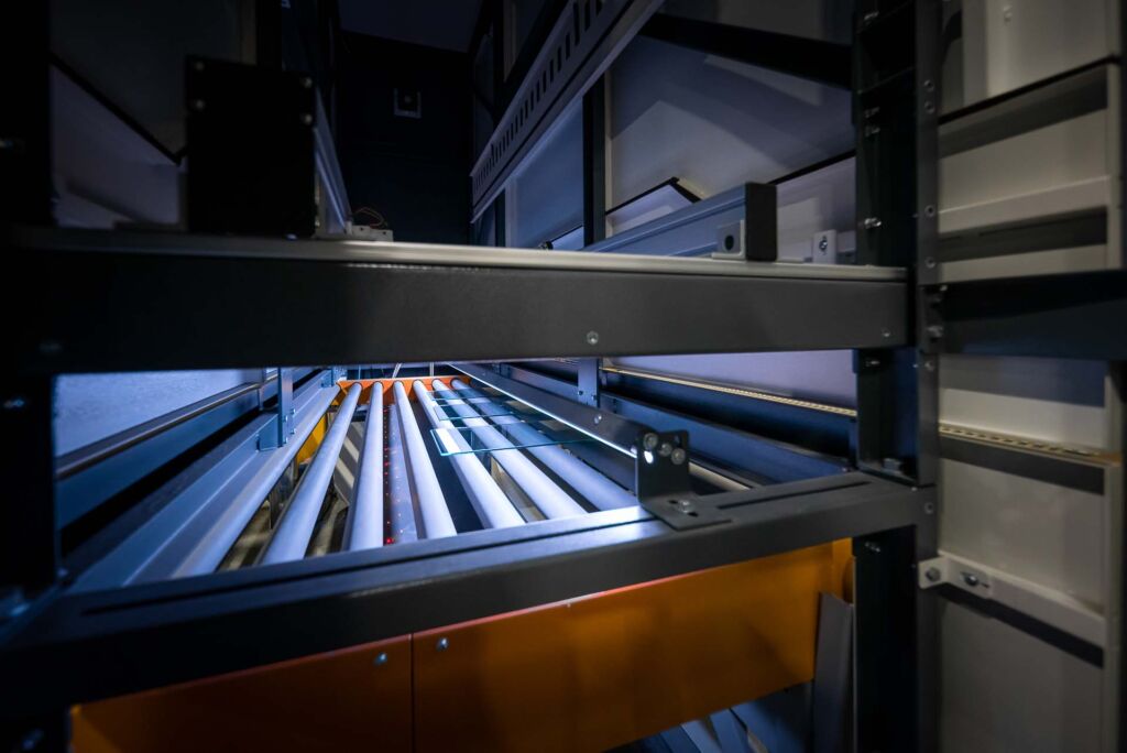 Glass sheets moving through blue conveyor rollers