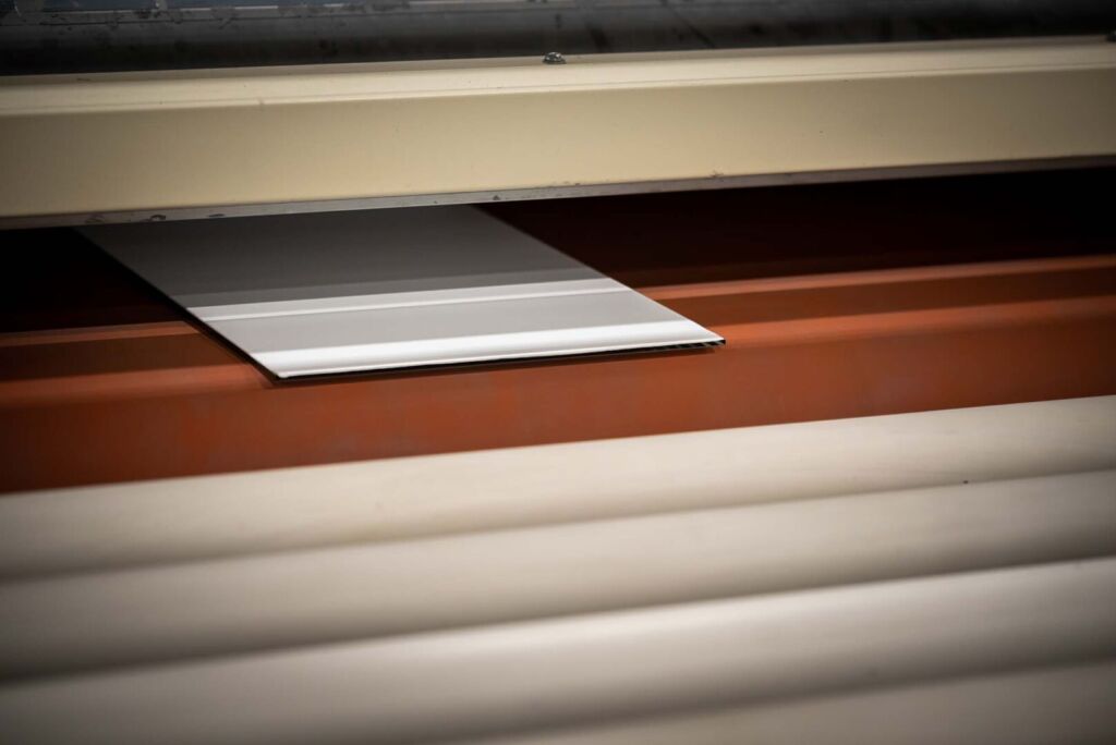 Glass pane on red rollers entering tempering oven