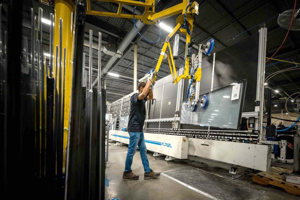 Technician operating overhead lift system for glass panel