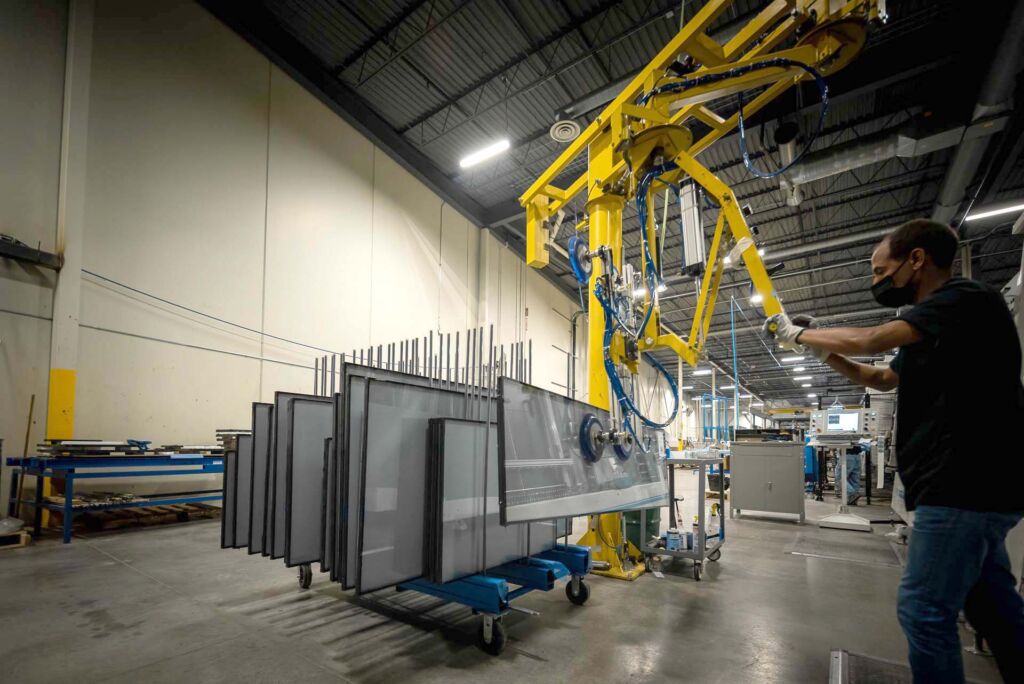 Glass panels loaded on metal racks inside clean facility