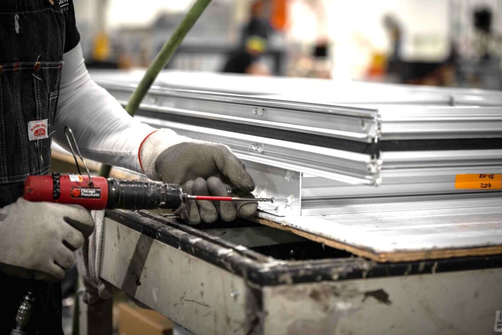 Gloved technician applying sealant to aluminum frame corner
