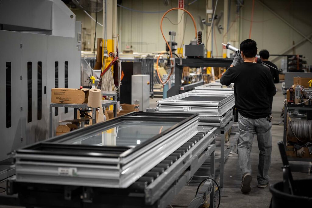 Team members inspecting and moving completed window units in shop