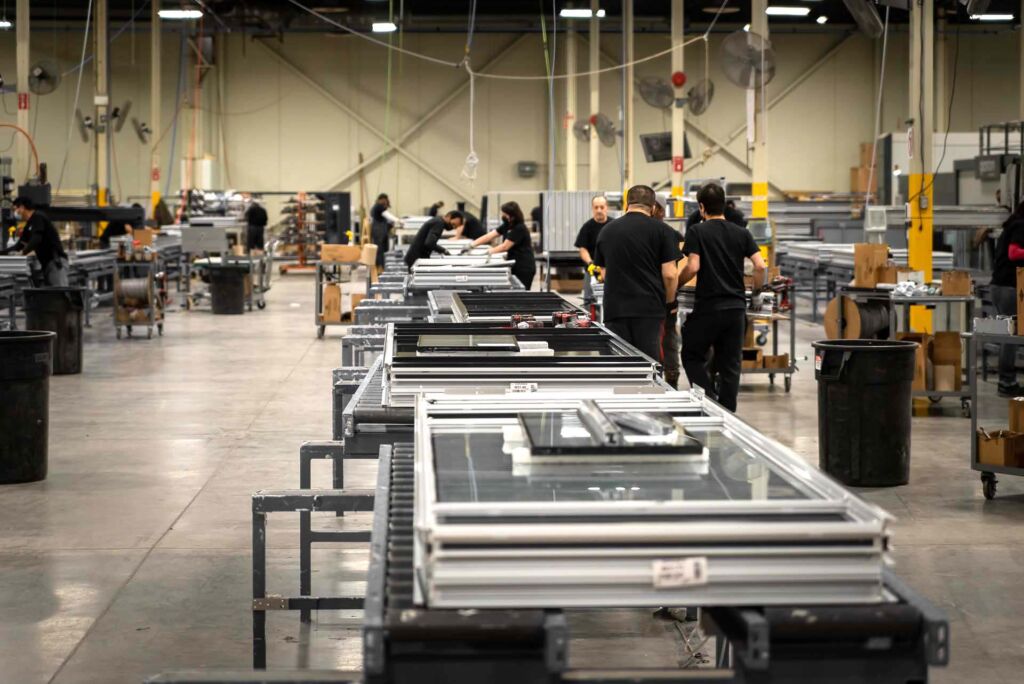 Assembly line workers constructing aluminum window frames
