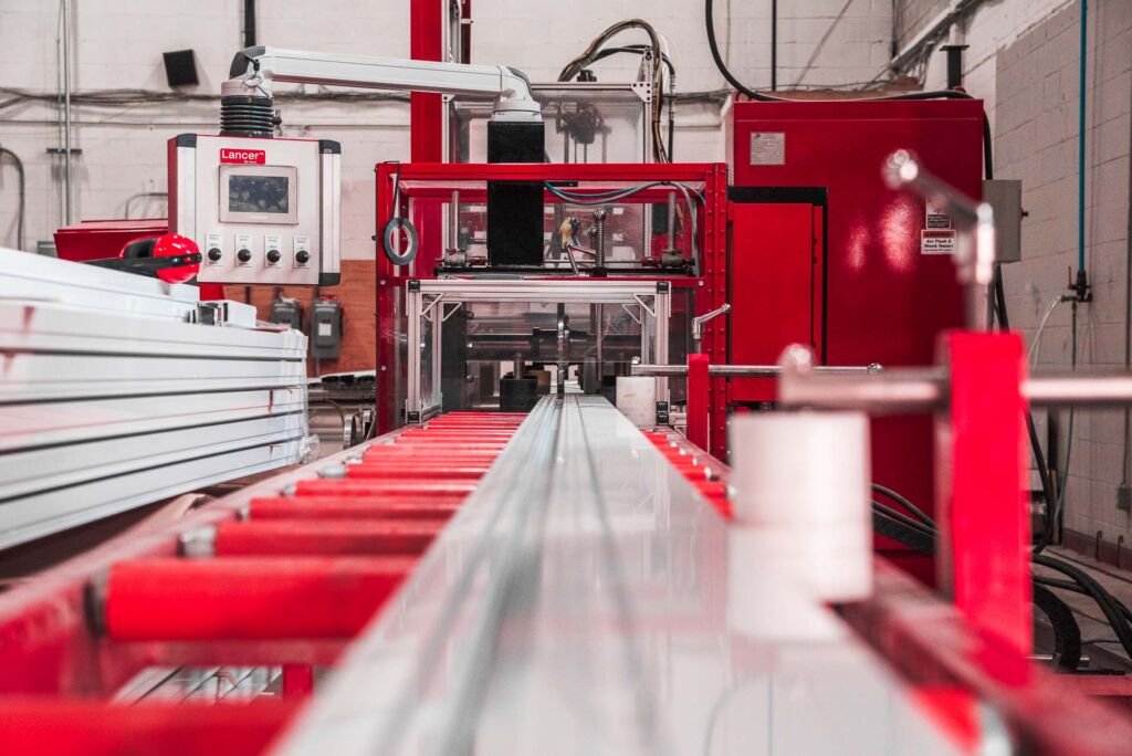 Aluminum extrusion line feeding material into a red CNC machine