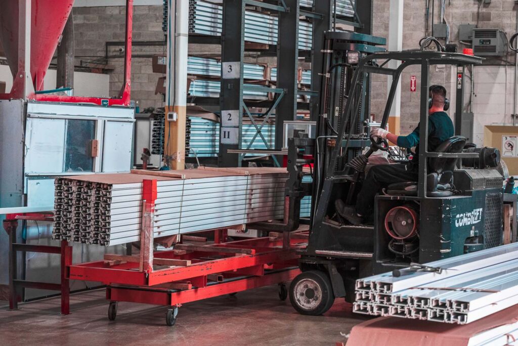 Forklift loading aluminum inventory in a busy warehouse