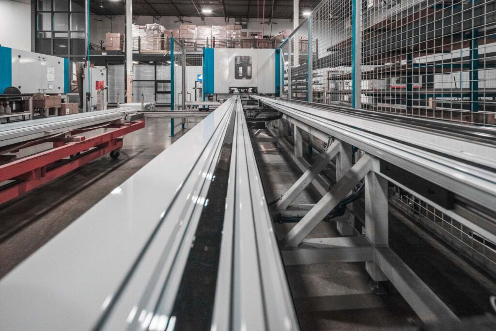 Long aluminum tracks lined up in a factory setting