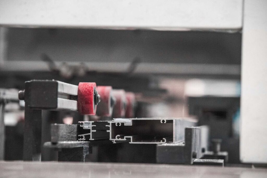 Close-up of automated machine placing red spacers on aluminum